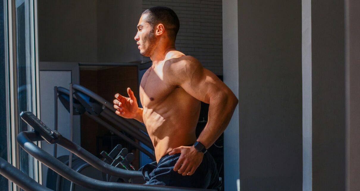 Man runs on a treadmill during a gym workout.