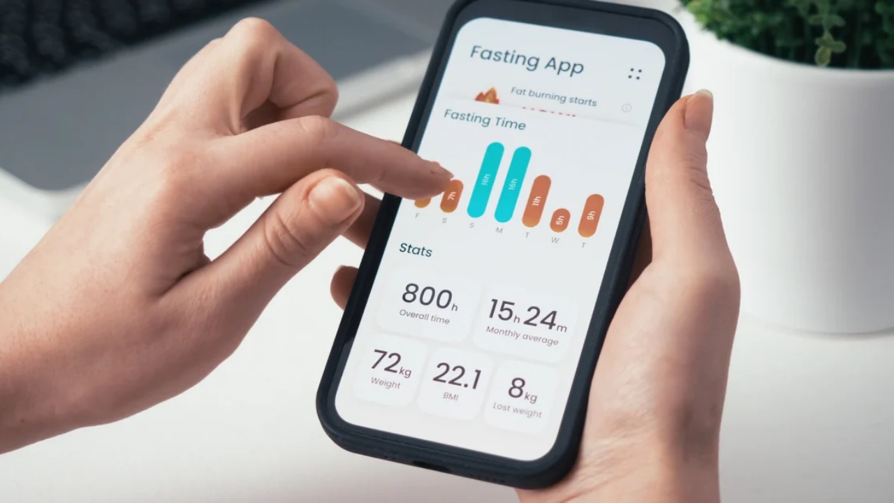 A person checks fasting hours and weight loss statistics on a smartphone app.