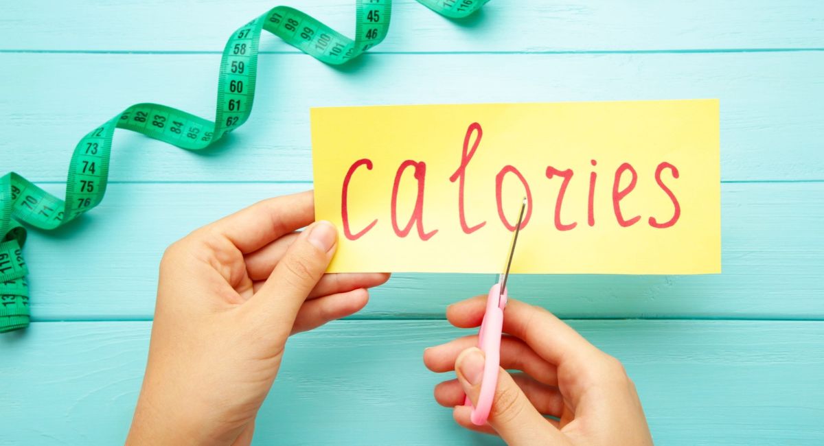Woman hand holding card with the word calories. Cutting calories. Top view