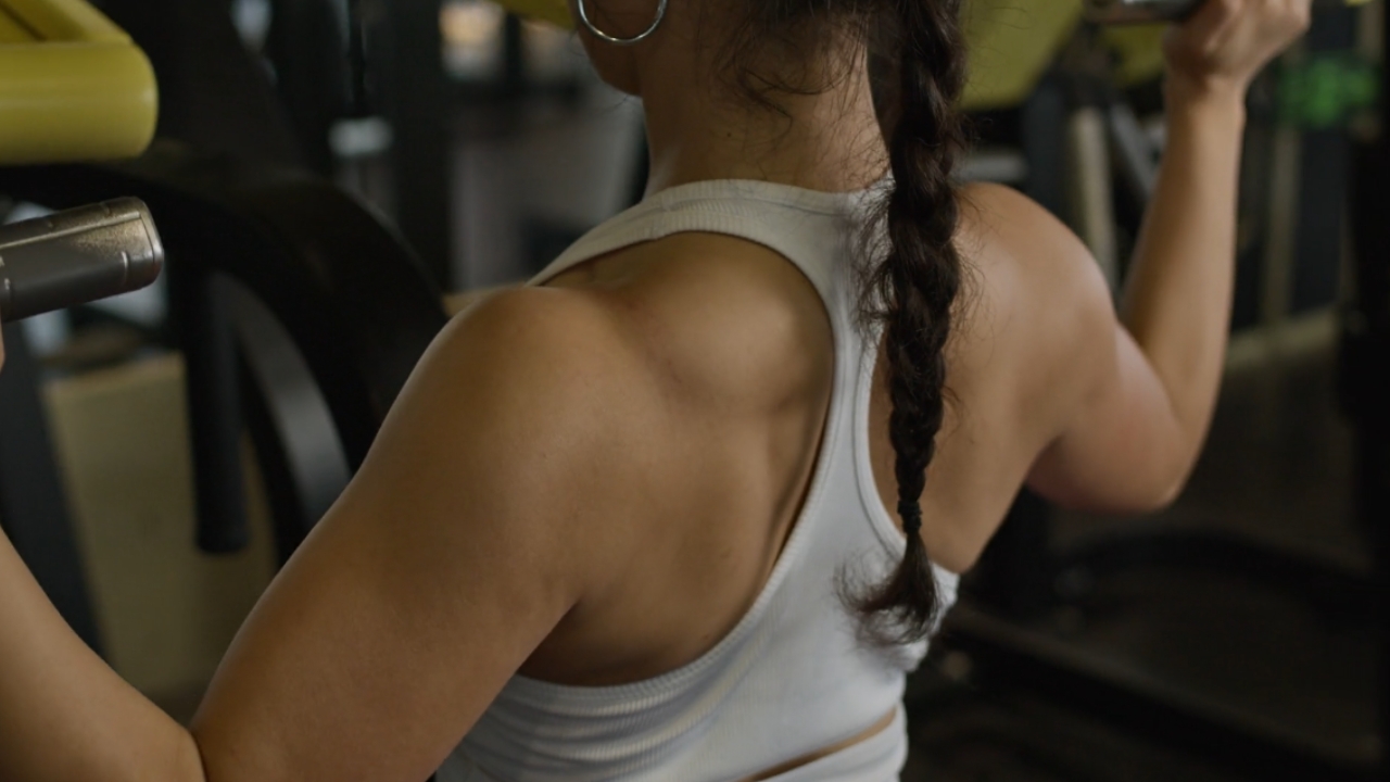 Woman performs a lat pulldown at the gym.