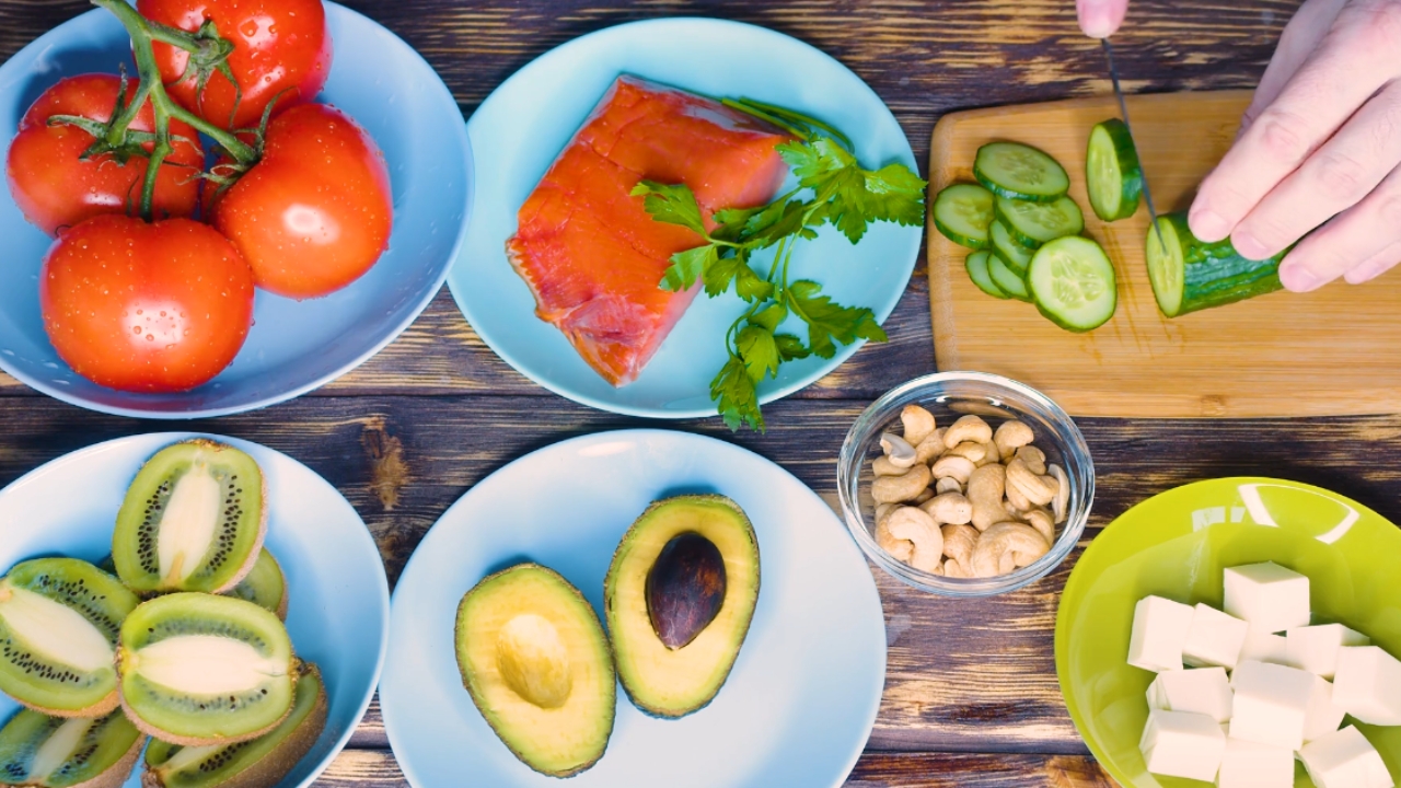 Keto-friendly foods including avocado, salmon, nuts, tofu, tomatoes, and cucumber.