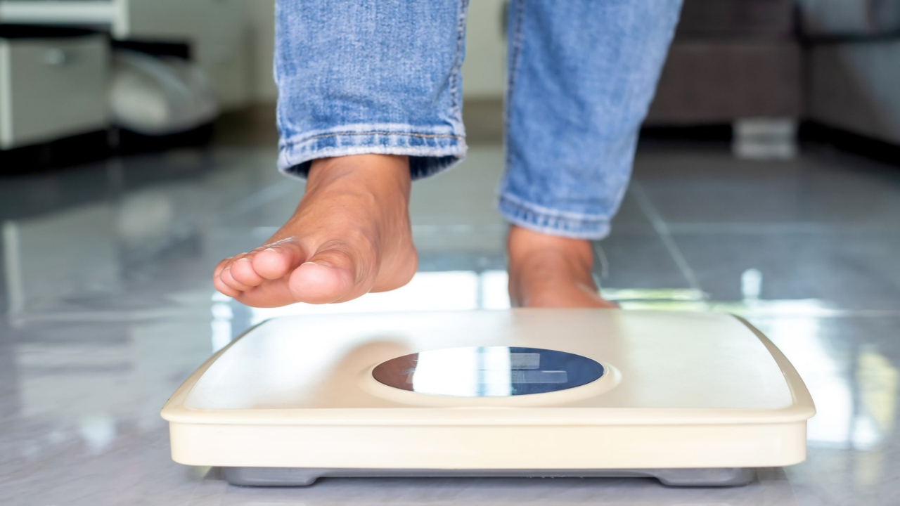 A person steps onto a digital bathroom scale to check their weight.